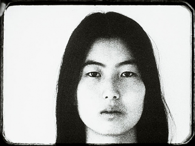 Black and white image of the head of an Asian woman looking at the camera.