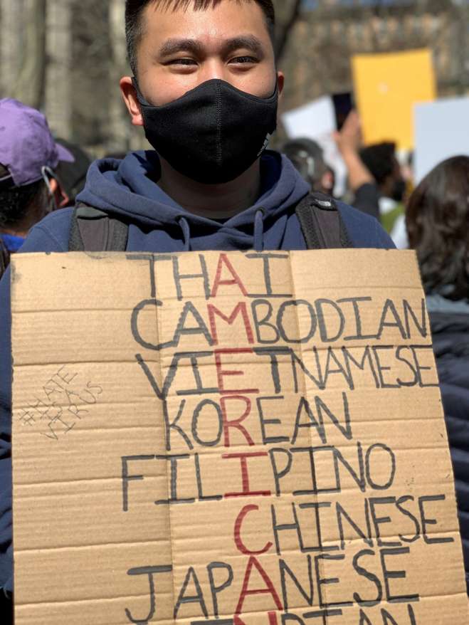 Photo of a young Asian man holding a sign at and Anti-Asian hate rally.