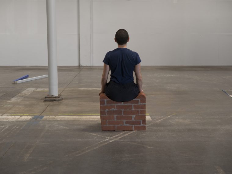Gordon Hall performing for Sitting (Brick Object) (III), carved brick, 2019. Image courtesy of Portland Institute for Contemporary Art and Evan La Londe