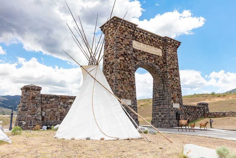 Image of a tipi next to a stone arch structure.