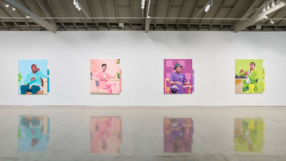 View of a gallery with four large colorful portraits of people.