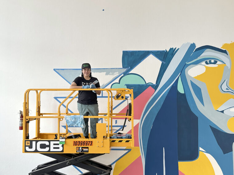 Artist Lynnette Haozous (Chiricahua Apache – San Carlos Apache Tribe, Diné, Taos Pueblo) installing her mural for Southwest Contemporary’s “12 New Mexico Artists to Know Now,” 2023, Photo by Suzanne Sbarge