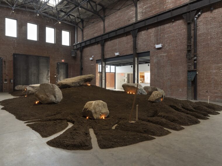 Édgar Calel, B’alab’äj (Jaguar Stone), 2023, installation view, Édgar Calel: B’alab’äj (Jaguar Stone), SculptureCenter, New York, 2023. Soil, rocks, audio, carved wood, hoes, candles, and offerings. Dimensions variable. Courtesy the artist and Proyectos Ultravioleta, Guatemala City. Commissioned by SculptureCenter, New York and Hartwig Art Foundation, Amsterdam. Photo: Charles Benton